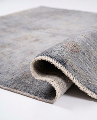 Close-up of grey-blue over-dyed wool rug floral medallion with rust-red accents