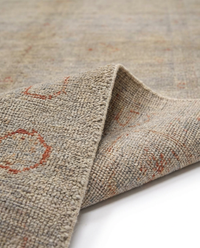 Grey-beige over-dyed wool rug folded to show pile texture