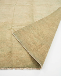 Sandy beige over-dyed wool rug folded diagonally to show pile