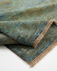 Teal blue over-dyed wool rug folded diagonally to show pile